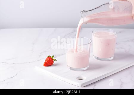 Versando kefir di frutta fatta in casa, latticello o yogurt con probiotici. Spazio di copia Foto Stock