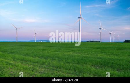 Incredibile vista delle turbine eoliche che generano energia rinnovabile all'interno di una distesa agricola, che coesistono armoniosamente con le attività agricole. Foto Stock