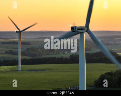 Vista aerea dall'alto dai mulini a vento in un gruppo di agricoltura, un tramonto luminoso. Ambiente verde e azienda eolica. Foto Stock