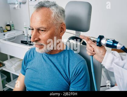 Medico ENT che esamina l'orecchio dell'uomo anziano usando l'endoscopio alla clinica otolaringologica. Endoscopia auricolare Foto Stock