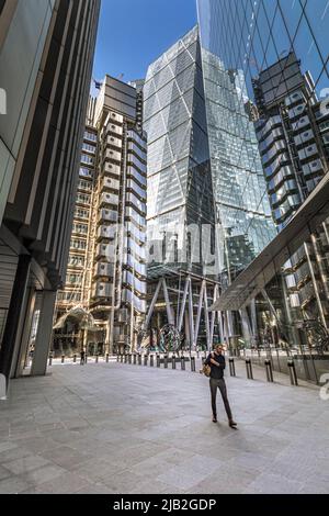 Un uomo cammina lungo Lime St nella città di Londra con il Lloyd's of London Building e il Leadenhall Building sullo sfondo, London EC3 Foto Stock