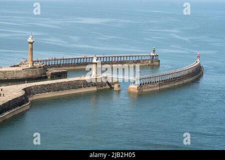 I moli e i fari all'ingresso del porto di Whitby nello Yorkshire, Inghilterra, Regno Unito Foto Stock