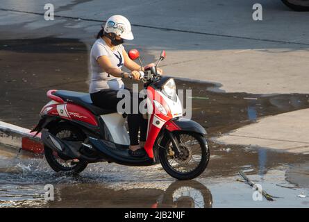 SAMUT PRAKAN, THAILANDIA, 28 2022 FEBBRAIO, Una donna con maschera di faccia corre una moto Foto Stock