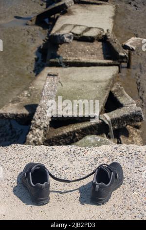 Le scarpe abbandonate al bordo della fine di un modo demolito Foto Stock