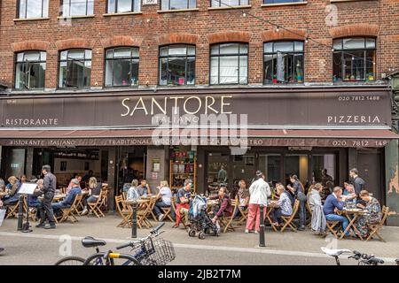 Persone seduti all'aperto ai tavoli gustando piatti italiani a Santore un ristorante e pizzeria italiana a Exmouth Market, Clerkenwell, Londra EC1 Foto Stock
