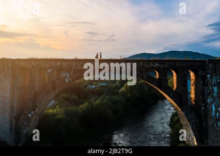 Vorokhta, Ucraina 28 luglio 2021: Un ragazzo e una ragazza camminano sul vecchio ponte, un viadotto in Ucraina, una passeggiata di spose. Foto Stock