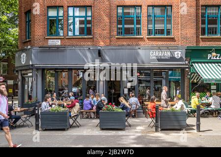 Persone seduti fuori Caravan una caffetteria, ristorante e bar situato in Exmouth Market, Clerkenwell, Londra EC1 Foto Stock
