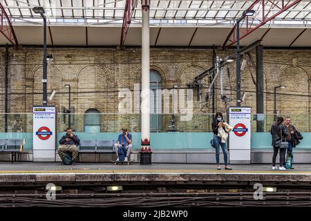 Persone in attesa sulla piattaforma della stazione per un treno della metropolitana di Londra alla stazione della metropolitana di Farringdon, Londra, EC1 Foto Stock