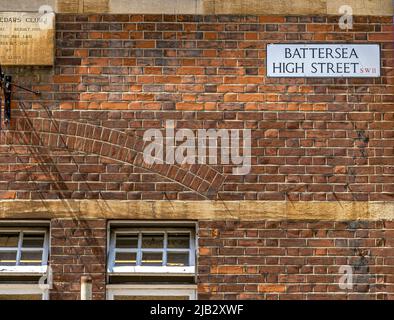 Il cartello con il nome della strada per Battersea High Street , in alto su una parete di mattoni rossi a Battersea , Londra, SW11 ,UK Foto Stock