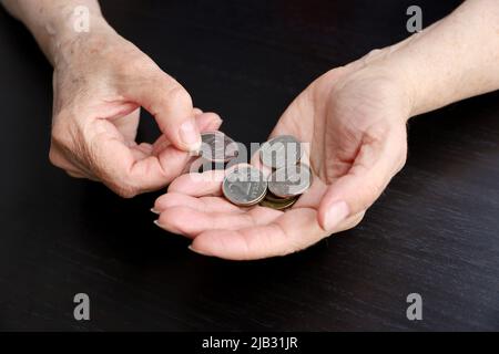 La donna anziana conta rubli russi in monete, le mani femminili rugose in primo piano. Concetto di povertà in Russia, pagamenti pensionistici Foto Stock