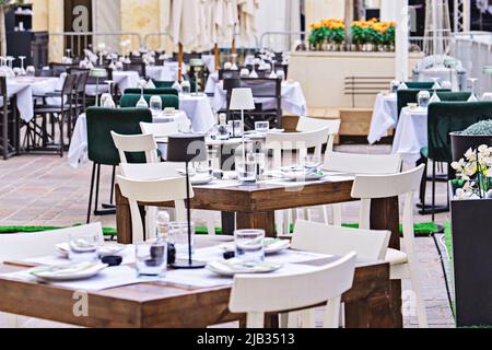 Vista generale dei tavoli serviti in un ristorante all'aperto, pronto ad accogliere i visitatori Foto Stock