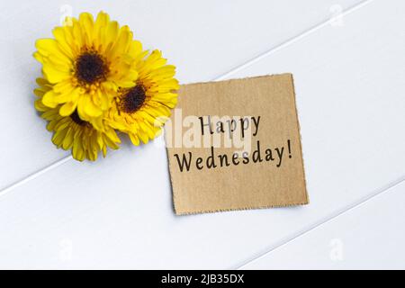 Testo del mercoledì felice su carta marrone strappata con girasole su sfondo bianco tavola di legno. Foto Stock