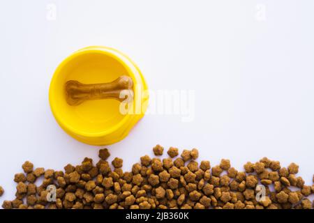 vista dall'alto del cane a forma di osso in una ciotola di plastica vicino al cibo per animali domestici Foto Stock