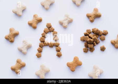 vista dall'alto di un animale a forma di osso tratta vicino alla lettera e cibo secco per animali isolati su bianco Foto Stock