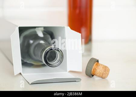 Due bottiglie, una piena vuota in scatole con cognac e un sughero sul tavolo in cucina, alcol sul tavolo a casa, una bottiglia di cognac Foto Stock