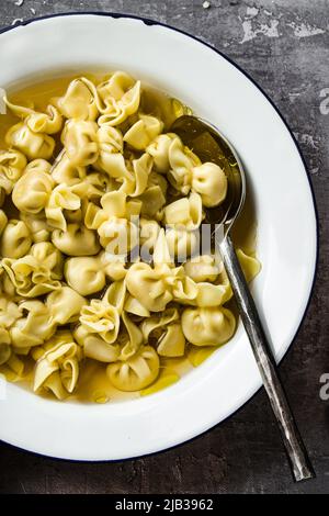 cappelletti in brodo. Piatto italiano per vacanze in famiglia. A tavola con parmigiano Foto Stock