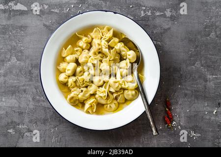 cappelletti in brodo. Piatto italiano per vacanze in famiglia. A tavola con parmigiano Foto Stock