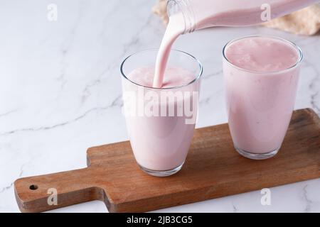 Versando kefir di frutta fatta in casa, latticello o yogurt con probiotici. Spazio di copia. Foto Stock