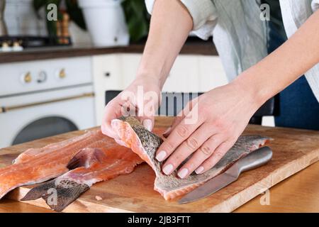 Le mani femminili tagliano il filetto di pesce rosso. Caviale rosso. Rimozione delle ossa di pesce. Carne di pesce rosso alla macelleria...concetto di cibo. Foto Stock