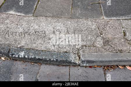 Messaggio "l'anarchia è la libertà" scritto in cemento bagnato sul marciapiede stradale a Penarth nel Galles del Sud Foto Stock