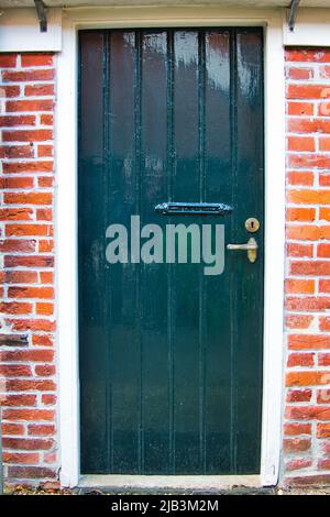 Porta rustica in legno verde scuro con maniglia in rame in una tradizionale casa colonica olandese Foto Stock