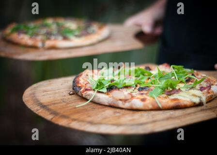 Pizza cotta a legna su tavola di legno in corso di trasporto Foto Stock