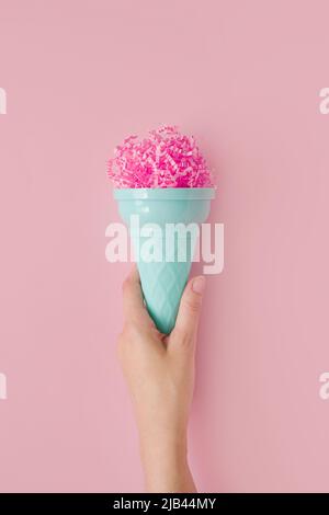 Paletta per gelato in carta rosa da donna con cono in plastica per gelato su sfondo rosa pastello. Concetto estivo minimo. Micro plastica negli alimenti Foto Stock