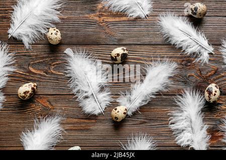 Uova di quaglia e belle piume su sfondo di legno Foto Stock