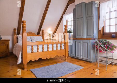 Antico letto a spole in legno e mobili da cucina blu riproposti in camera da letto degli ospiti all'interno ricostruita 1800s casa di tronchi. Foto Stock
