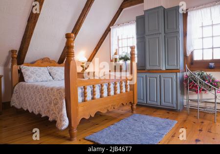 Antico letto a spole in legno e mobili da cucina blu riproposti in camera da letto degli ospiti all'interno ricostruita 1800s casa di tronchi. Foto Stock