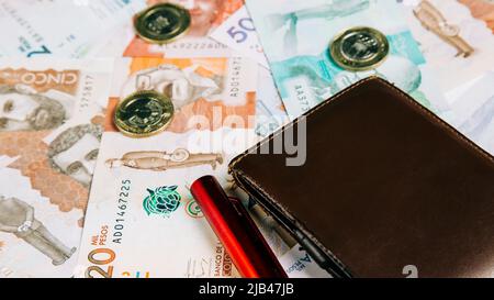 Denaro colombiano in diverse denominazioni con un portafoglio Foto Stock