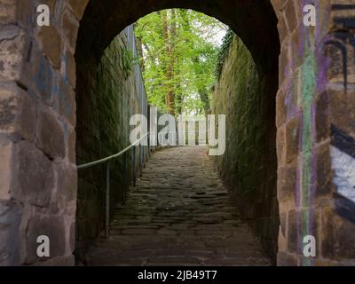 Misterioso percorso tra antiche mura costruite con pietre naturali. Edificio esterno di architettura storica nei boschi. Avventura in un parco. Foto Stock