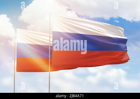 Cielo azzurro soleggiato e bandiere di russia e russia Foto Stock