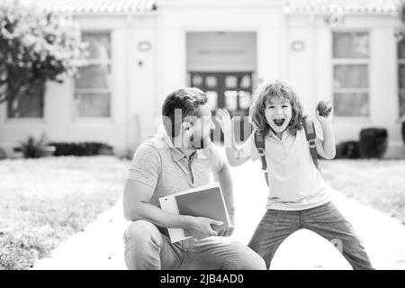 Giornata degli insegnanti. Padre e figlio camminano attraverso il parco scolastico. Genitore che porta il bambino a scuola. Foto Stock