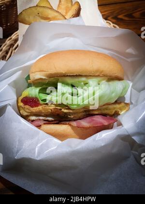 Deliziose omelette, lattuga e hamburger con pancetta in carta da imballaggio nel ristorante di Kumamoto, Giappone. Foto Stock