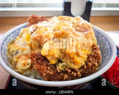 Katsudon, una ciotola di riso con una cotoletta di maiale fritta, uova, verdure e condimenti, con sottaceti Tsukemono in un ristorante locale in Giappone. Foto Stock