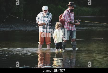 Ritratto di piccolo figlio felice, padre e nonno - tre generazioni di uomini che pescano sul fiume. Pesca nel fiume. Nonno con figlio e nipote Foto Stock