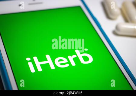 Kumamoto, Giappone - Lug 23 2020 : primo piano del logo iHerb su iPhone con capsule mediche (pillole) che si trova a caso. Foto Stock