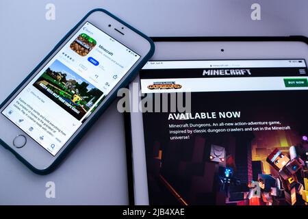 Minecraft in App Store su iPhone e Minecraft Dungeons sito web su iPad in background. Minecraft è un videogioco di sandbox sviluppato da Mojang Studios Foto Stock