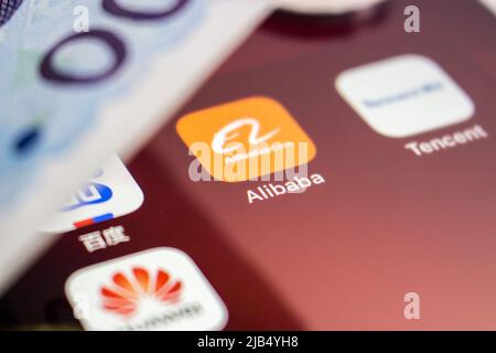 Logo Alibaba, fondato il 4 aprile 1999 a Hangzhou, Zhejiang, con loghi cinesi di grandi aziende tecnologiche (Baidu, Tencent e Huawei) e denaro su un iPhone. Foto Stock