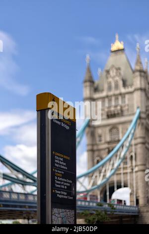 LONDRA, UK - 01 GIUGNO 2022: Ufficio informazioni turistiche con le indicazioni per Tower Bridge e vista sfocata del Tower Bridge sullo sfondo Foto Stock