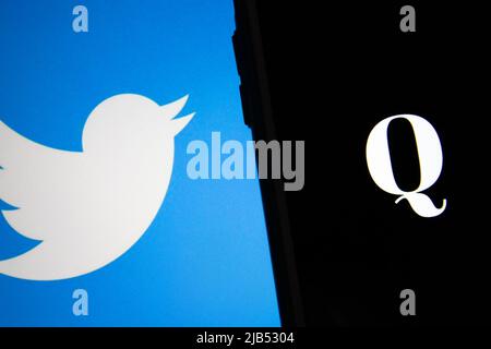 Kumamoto / GIAPPONE - Ott 20 2020 : il logo di Qanon, un gruppo di cospirazione di estrema destra, su iPhone con il logo Twitter come sfondo. Foto Stock