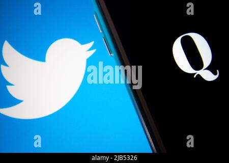 Kumamoto / GIAPPONE - Ott 20 2020 : il logo di Qanon, un gruppo di cospirazione di estrema destra, su iPhone con il logo Twitter come sfondo. Foto Stock