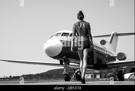 Stewardess in blu uniforme - vista posteriore. Piuttosto assistente di volo femminile in aeroporto. Affascinante stewardess vestita in uniforme blu. Viaggi e jet Foto Stock