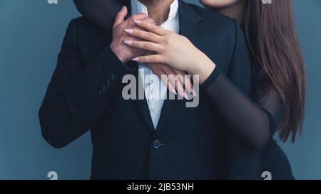 Closeup studio girato di mani di una donna caucasica con belle unghie lunghe e bella tenuta manicure abbracciando un uomo in un abito nero elegante. Foto di alta qualità Foto Stock