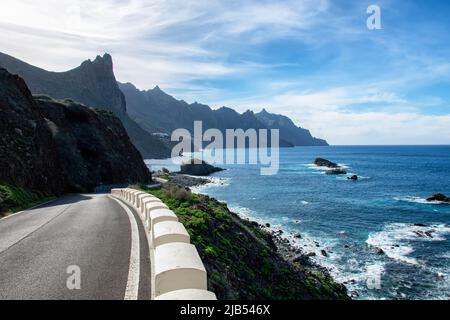 La strada nelle montagne di Anaga, sullo sfondo è l'Oceano Atlantico Tenerife, mare blu sulle pendici verdi delle montagne lungo la pa Foto Stock