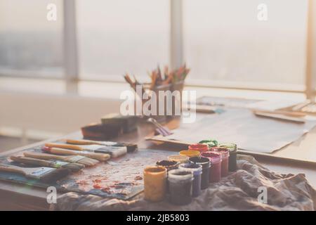 Foto con angolo di visualizzazione della tavolozza con vernici a olio misto, gouache, pastelli e pennelli impostati in studio d'arte Foto Stock