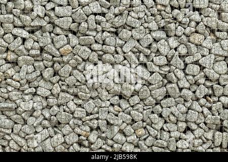 Sfondo testurizzato di un muro di pietra con rete di ferro. Muro di pietra nel telaio di filo. Foto Stock