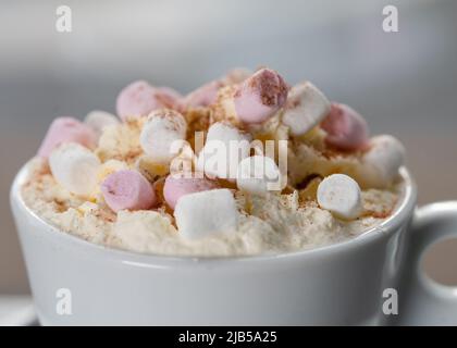 tazza di caffè o cioccolata calda con marshmallow sul tavolo in caffetteria contro la finestra nella notte invernale nevoso Foto Stock