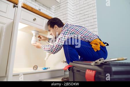 Idraulico che fissa alcuni problemi con il lavello della cucina, riparando i tubi o disintasando il blocco Foto Stock